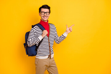 Photo of young guy happy smile indicate finger empty space ad promo advice choose bag education isolated over yellow color background
