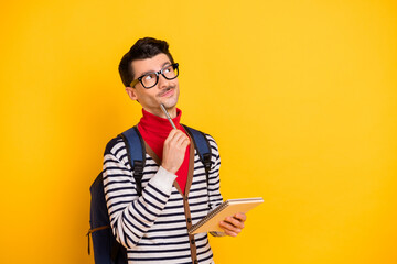 Photo of young man think dream look empty space inspiration write notebook education isolated over yellow color background