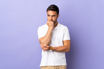 Young handsome man isolated on purple background having doubts
