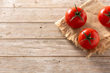 Organic fresh tomatoes on rustic wooden table. Top view. Copy space
