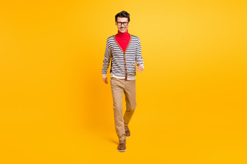 Fototapeta premium Full body portrait of satisfied young man walking toothy smile look camera isolated on vibrant yellow color background