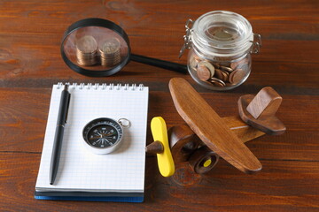 The still life from objects about ideas of travel, tourism, transportation and cost on the brown wooden background. The concepts of rest, travel, tourism, adventure and planning. 