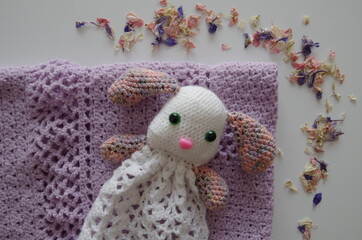 cadeau de naissance : peluche lapin fait au crochet, blanc et multicolore, sur une couverture...