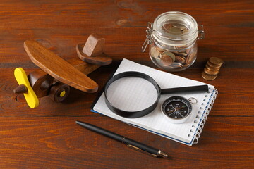 The still life from objects about ideas of travel, tourism, transportation and cost on the brown wooden background. The concepts of rest, travel, tourism, adventure and planning. 