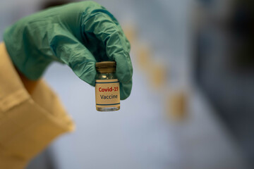 nurse or doctor with blue gloves holding bottle of COVID-19 vaccine. Healthcare And Medical concept.