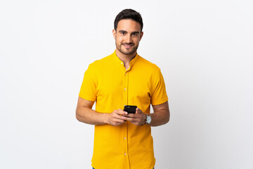 Young handsome man over isolated background sending a message with the mobile