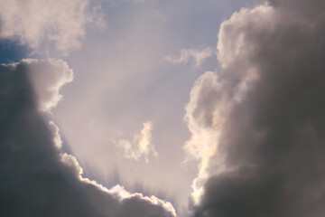 A stormy black cloud against a dark sky with rays of the sun