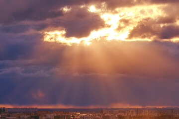 Dark clouds in the red evening sky with the rays of the sun, sunset background