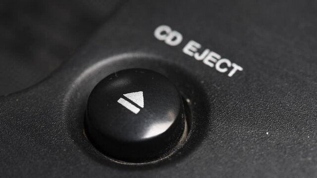 Close-up of a man's finger presses the mechanical button for ejecting a cd disc from a retro turntable
