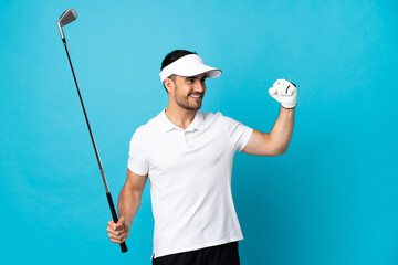 Young handsome man isolated on blue background playing golf and celebrating a victory