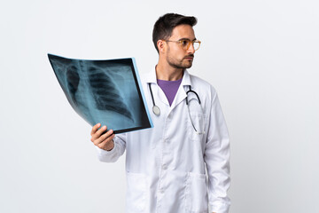 Young doctor man holding a radiography isolated on white background looking side