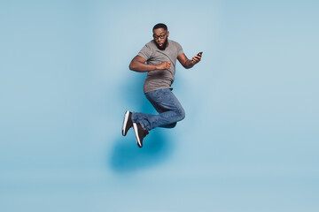 Full size photo of afro american guy jump cellphone isolated blue color background