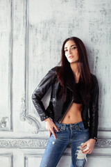 young brunette woman in leather jacket at vintage wall