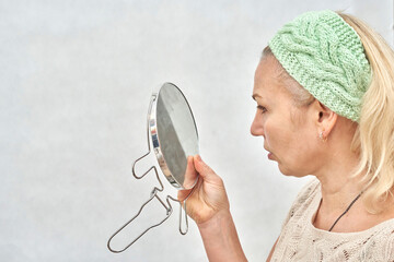 A woman aged looks in the mirror before applying makeup