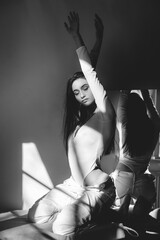portrait of beautiful gentle woman in a white bodysuit posing in the sunshine. Black long hair. sensuality and tenderness