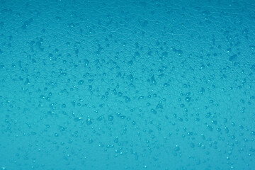 Tropfen auf türkis farbender Oberfläche als Hintergrund