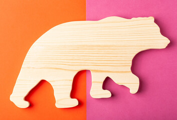 A figurine of a bear carved from solid pine by a hand jigsaw. On a multi-colored background.