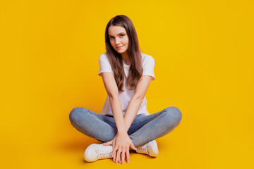 Photo of carefree tempting lady sit floor crossed legs wear white t-shirt posing on yellow background