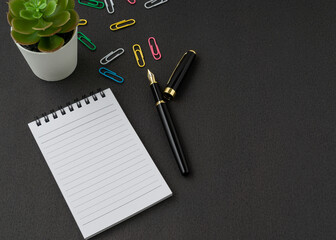 A notebook and pen on black background with a copy space. Business and finance concept.