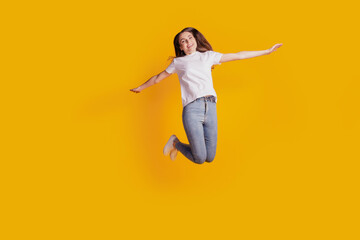 Photo of dreamy carefree lady jump enjoy weekend fun wear white t-shirt posing on yellow background