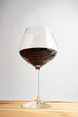 Elegant wineglass with red wine on bright vintage wooden background