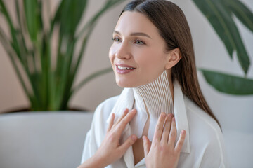 Cute young woman visiting beauty center and having taping procedure on her neck muscle