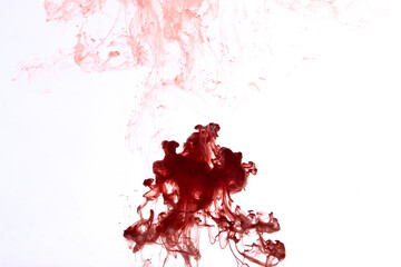 Red paint dissolving in water creating abstract shapes