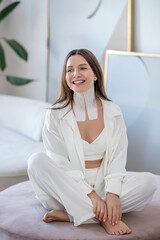 Obraz premium Young woman in white sitting in a room with tapes on her neck