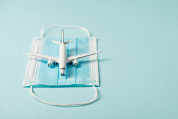 Closeup photo of plane model on medical mask isolated blue background with copyspace