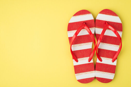 Top view photo of striped red and white flip-flops on isolated yellow background with copyspace