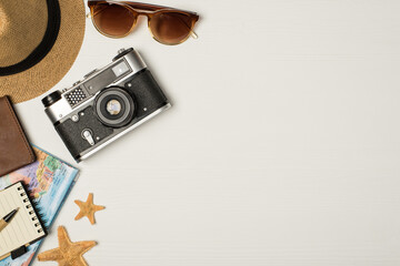 Top view photo of headwear sunglasses camera map passport cover starfishes pen and notebook on isolated wooden white background with copyspace on the right