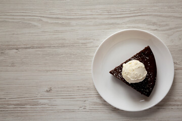 Homemade Chocolate Cake with Ice Cream on a white plate on a white wooden background, top view. Flat lay, overhead, from above. Copy space.