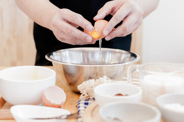 Man in the kitchen cooking a dough. Hands breaks an egg into a bowl ,hands pouring bitten egg ,Baking concept