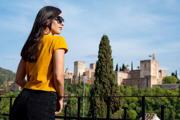 Female traveler in sunglasses standing on terrace and enjoying sunny weather while visiting Granada, Spain