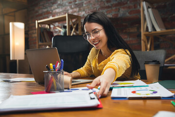 Young woman working in modern office using devices and gadgets. Making reports, analitycs, routine processing tasks