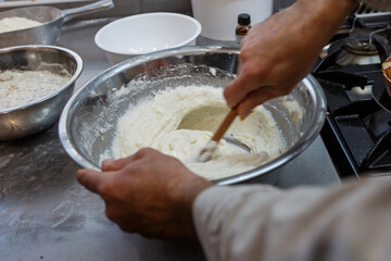 Pasticciere specializzato mentre lavora l'impasto di un dolce con ricotta in una bull d'acciaio