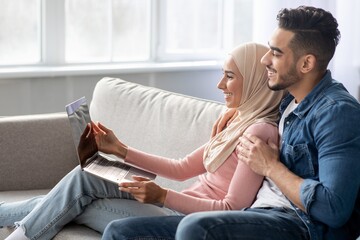 Side view of muslim couple using laptop at home