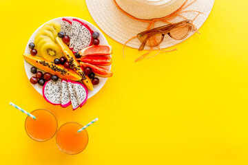 Straw hat and exotic tropical fruits top view. Vacation and diet concept