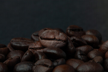Roasted coffee beans on the old dark wooden background for wallpaper or decor. Shallow depth of field. Selected focuse