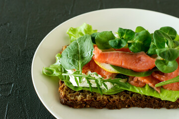 Sandwich with smoked salmon soft cheese, lattice and lemon. Concept for a tasty and healthy meal. Food on a plate.