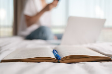 An open book with a pen and a close-up. In the background, a blurry silhouette of a woman. Concept...