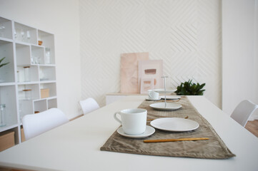 Light white kitchen with white chairs. Lunch area. A large light space.