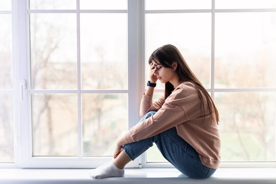 Sad woman crying near window at home