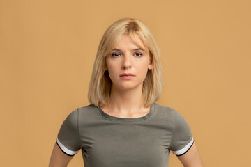 Natural beauty. Portrait of blonde millennial woman with calm facial expression, beige studio...