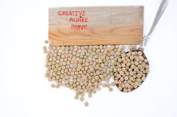 creative ,aware,brave and the yellow brown peas seeds in spoon isolated on white background.
