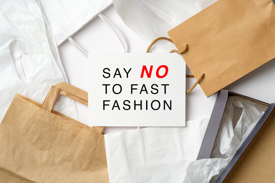 Say No To Fast Fashion sign on paper card over heap of shopping bags. Fast Fashion is bad for the environment