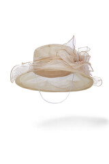 Subject shot of beige organza hat with chin strap and decorated with large tissue flower. Stylish hat for evening party is isolated on the white backdrop.