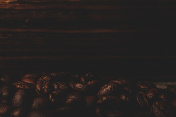 Roasted coffee beans on the old dark wooden background for wallpaper or decor