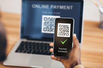 Black man scanning qr code from laptop with smartphone