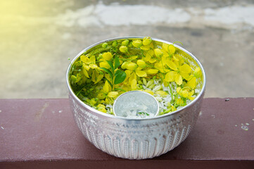 A bowl made of silver with fragrant flowers and water in a bowl, for use in Thai Songkran traditions.